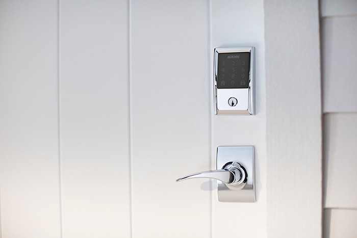 White paneled front entry door with a wifi-enabled deadbolt lock
