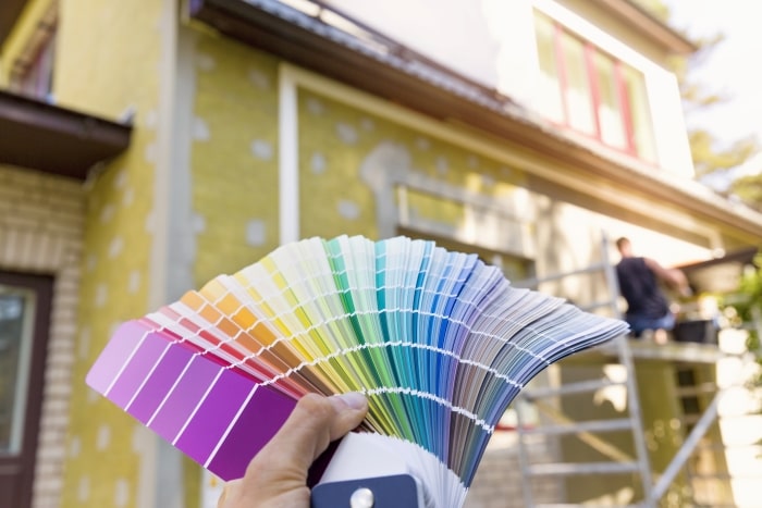 Book of paint samples next to exterior of house.