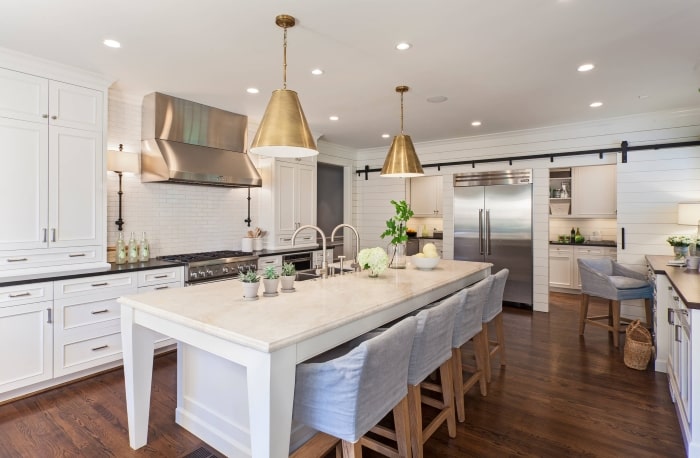 White kitchen with gold lighting and black hardware.