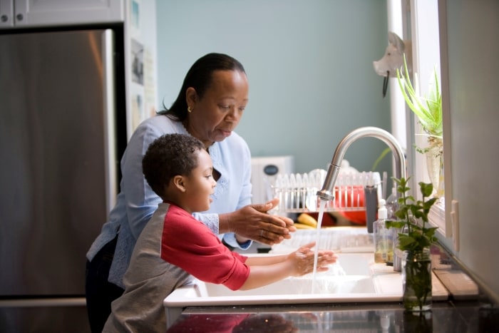 Mother and son washing hands in the kitchen.