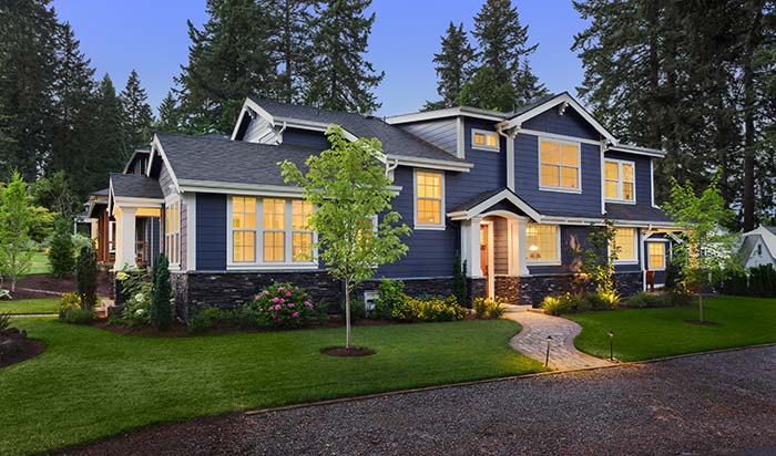 suburban home with blue siding lit up at night
