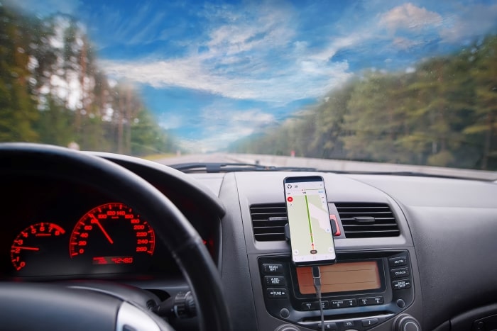 Car with smartphone mounted to dash showing navigation.