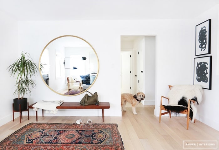 Entryway with large round gold trim mirror.
