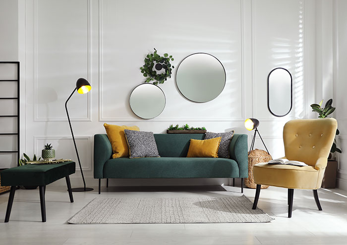 Modern living room with mirrors on wall and velvet furniture.