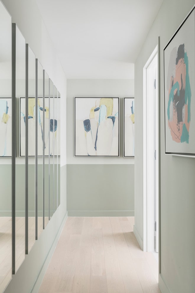 Narrow hallway with mirrors and mid century artwork.