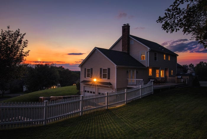 Country home at night with lights on.