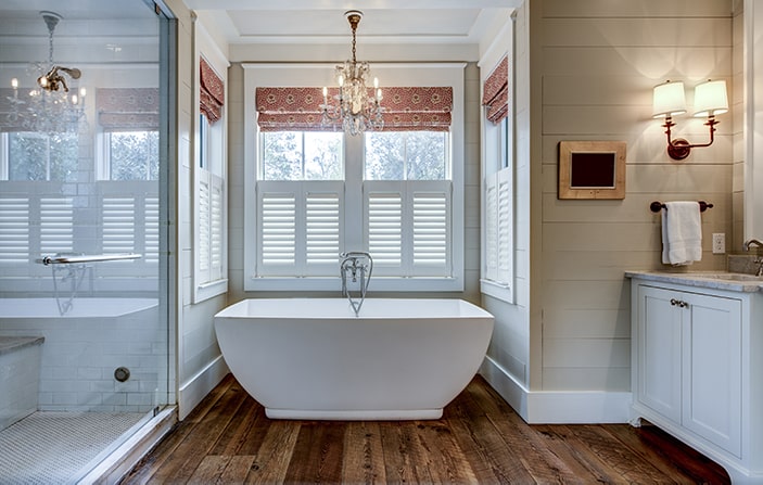 Farmhouse chic bathroom with freestanding bathtub and chandelier.