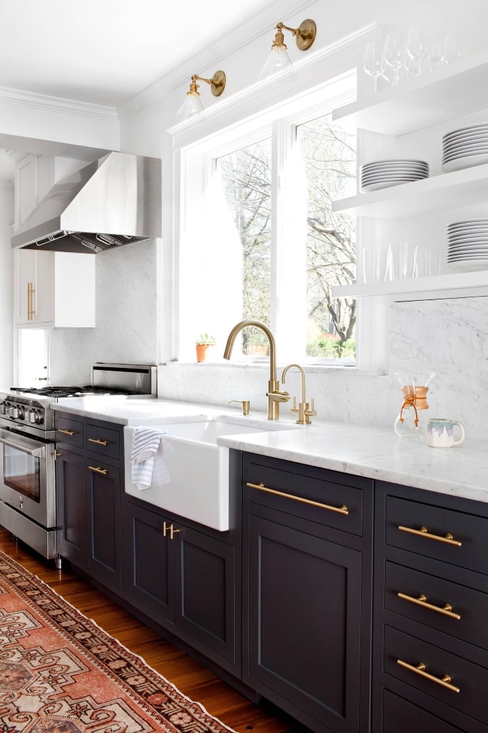 Navy kitchen cabinets with marble countertop and brass fixtures.