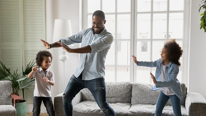 Dad dancing in living room with his two kids.