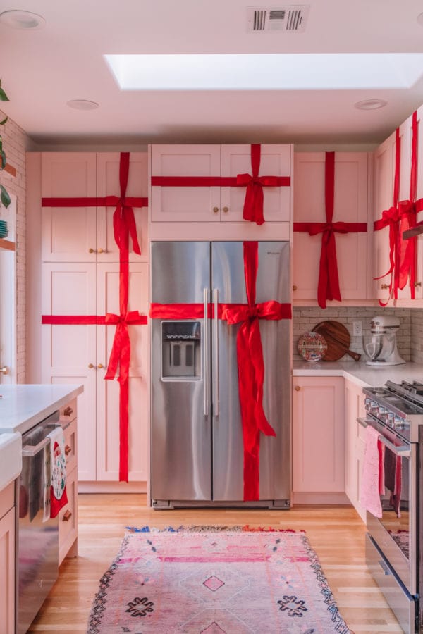 Kitchen cabinets wrapped in red ribbon for Christmas.