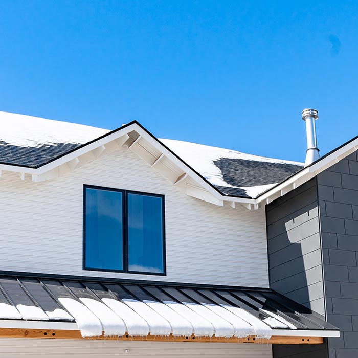 Modern farmhouse exterior with snow on roof.