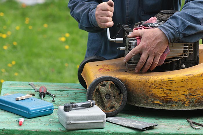 Man working on old push lawnmower.