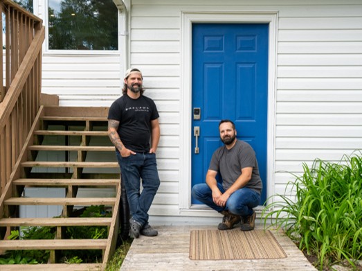 The Brolaws in front of a back entryway on their cottage that features Schlage's Encode Plus deadbolt with a matching nickel handelset