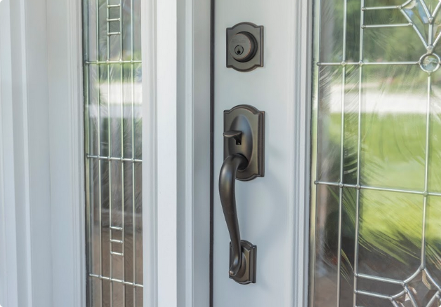 Close up of a white front door with a dark gray matching deadbolt and handle.