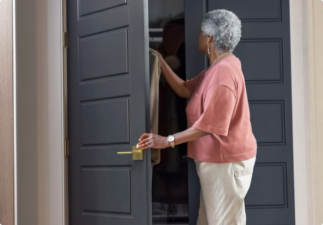 Woman opening her closet door which is painted dark brown and has satin brass door levers.