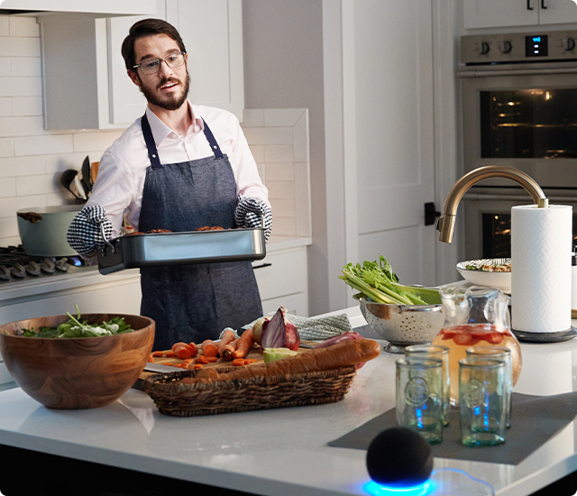 Man speaking to Echo smart speaker while cooking in the kitchen.