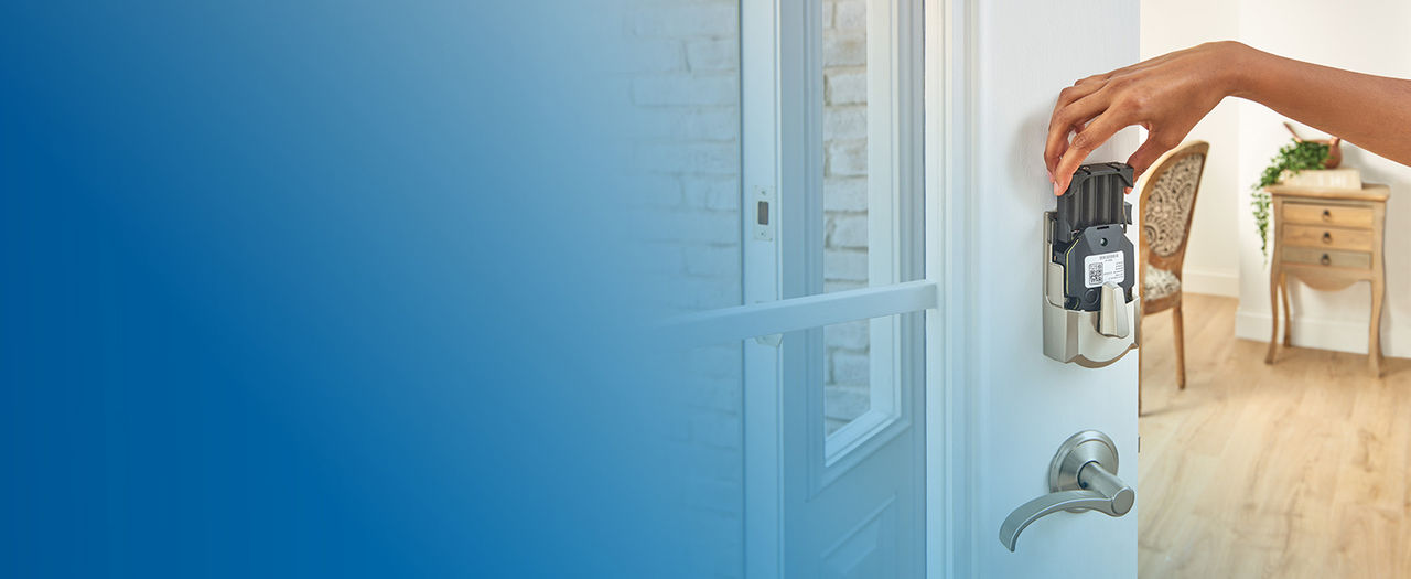 Person removing battery pack from Schlage Encode Plus Smart Lock installed on open front door